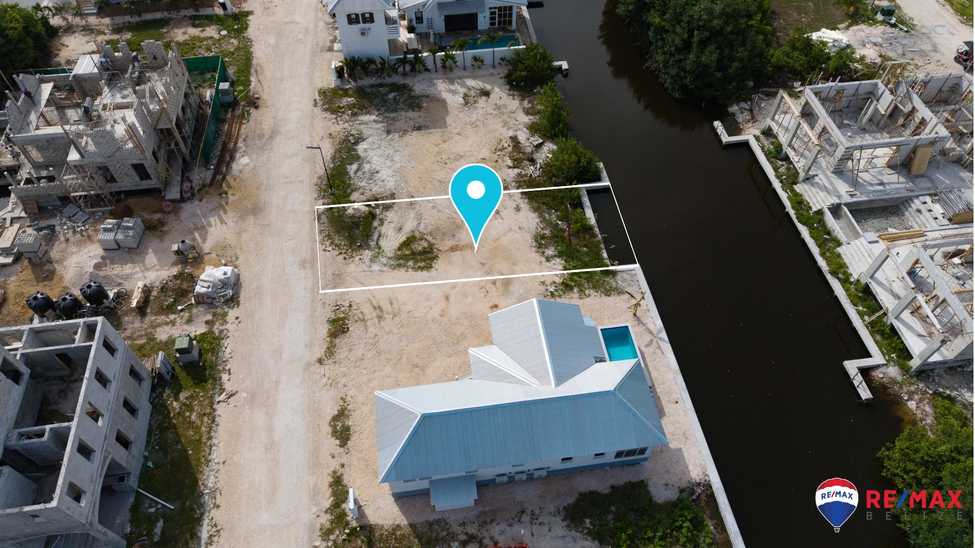 Aerial view of cleared lot outlined beside a canal with neighboring homes