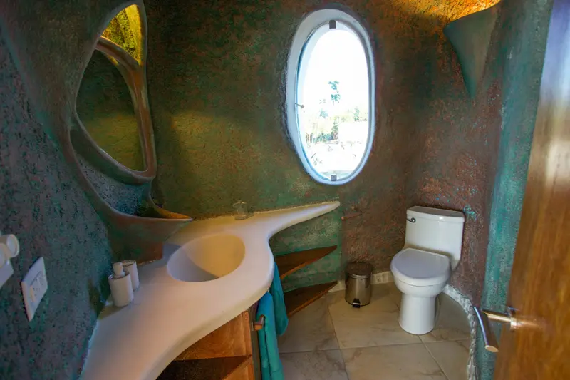 Bathroom with mottled green wall, oval window and white sculpted vanity