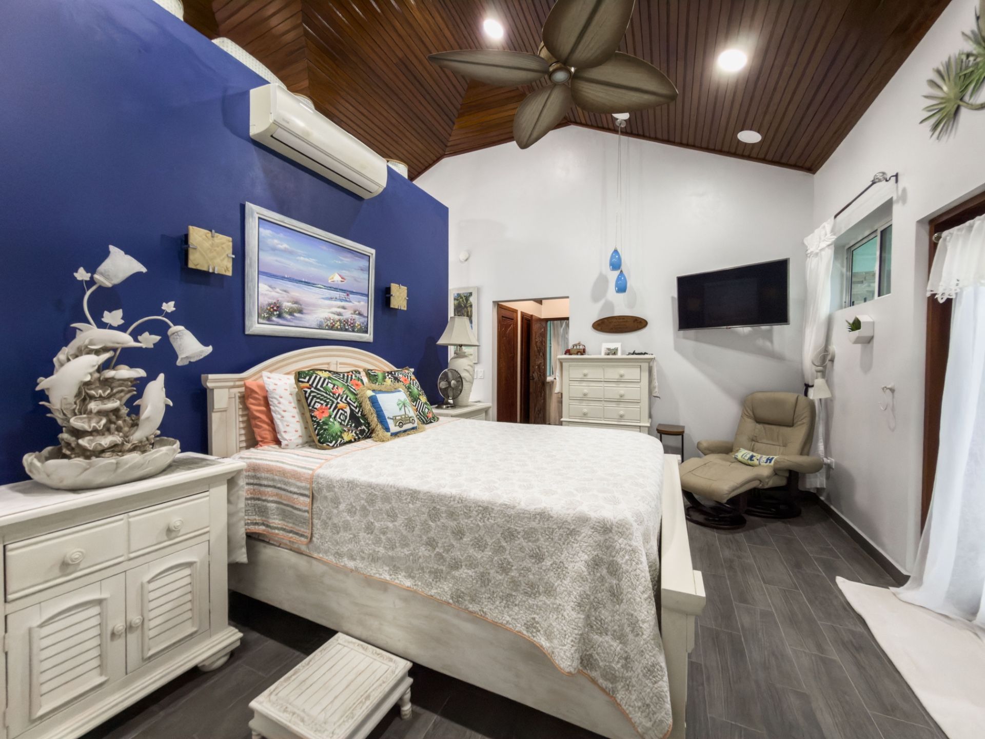 Bedroom with navy accent wall, wood-paneled ceiling and white queen bed