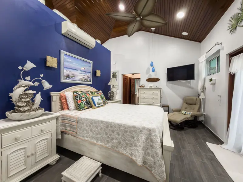Bedroom with navy accent wall, wood-paneled ceiling and white queen bed