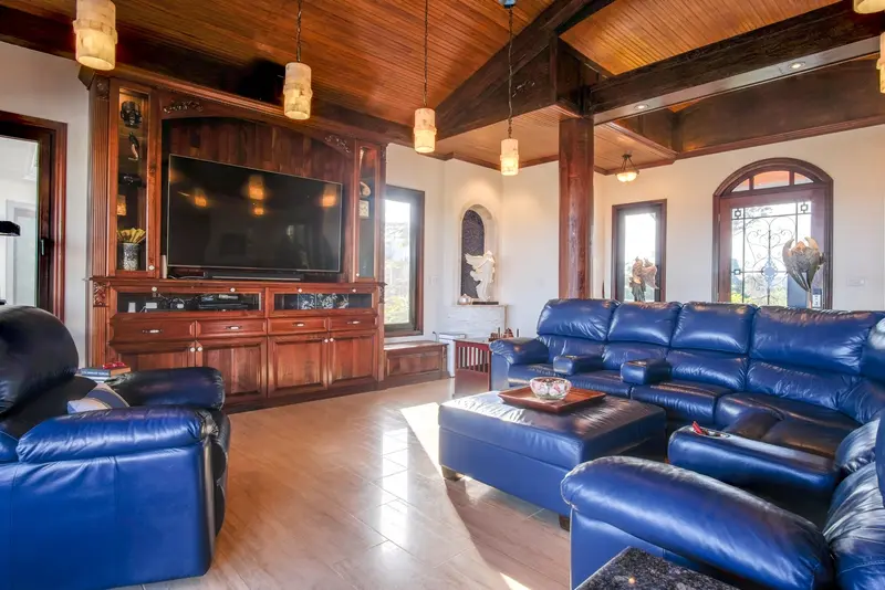 Living room with blue leather sofa, wall-mounted TV and wood cabinetry