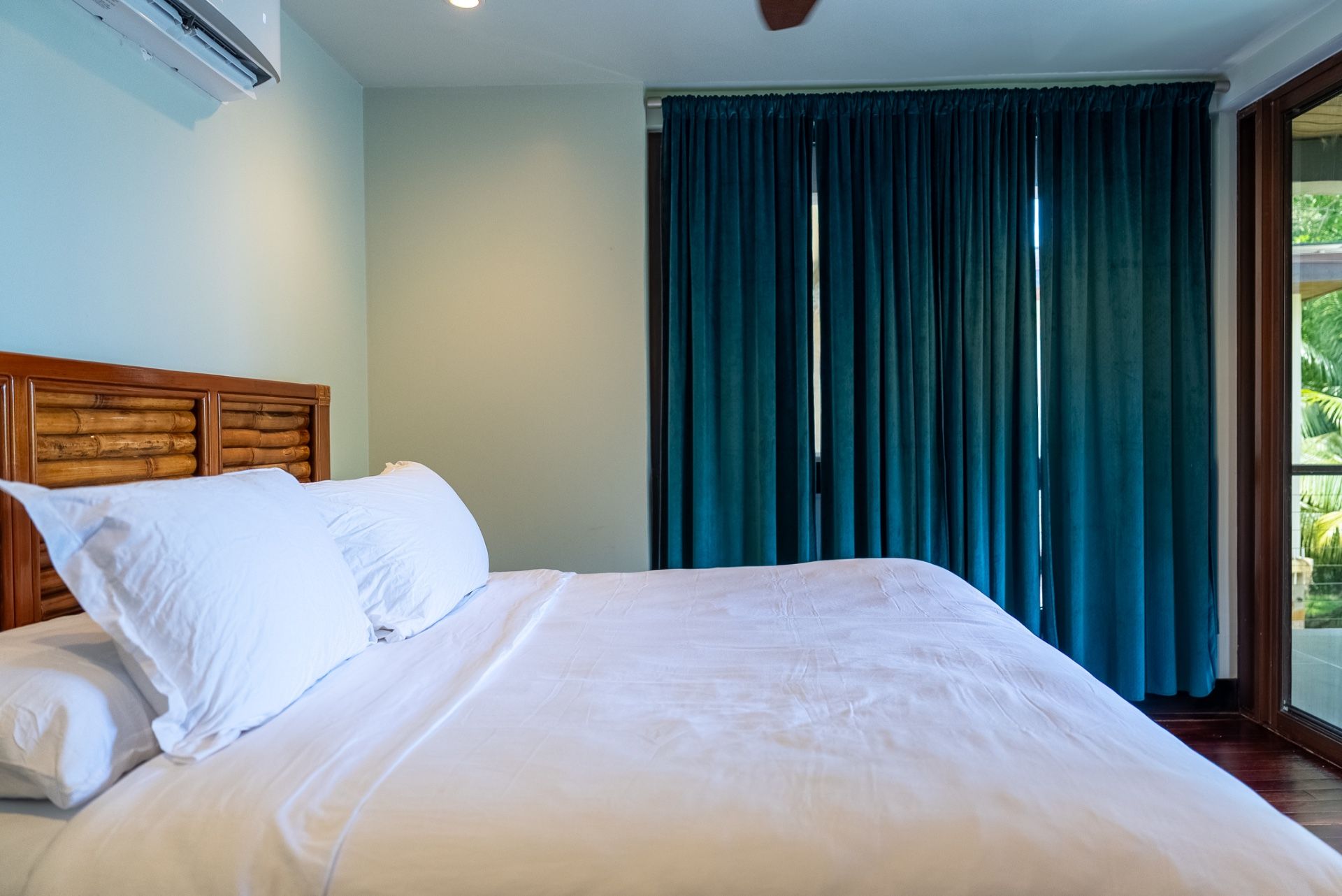 Bedroom with white bed linens and teal velvet curtains at window