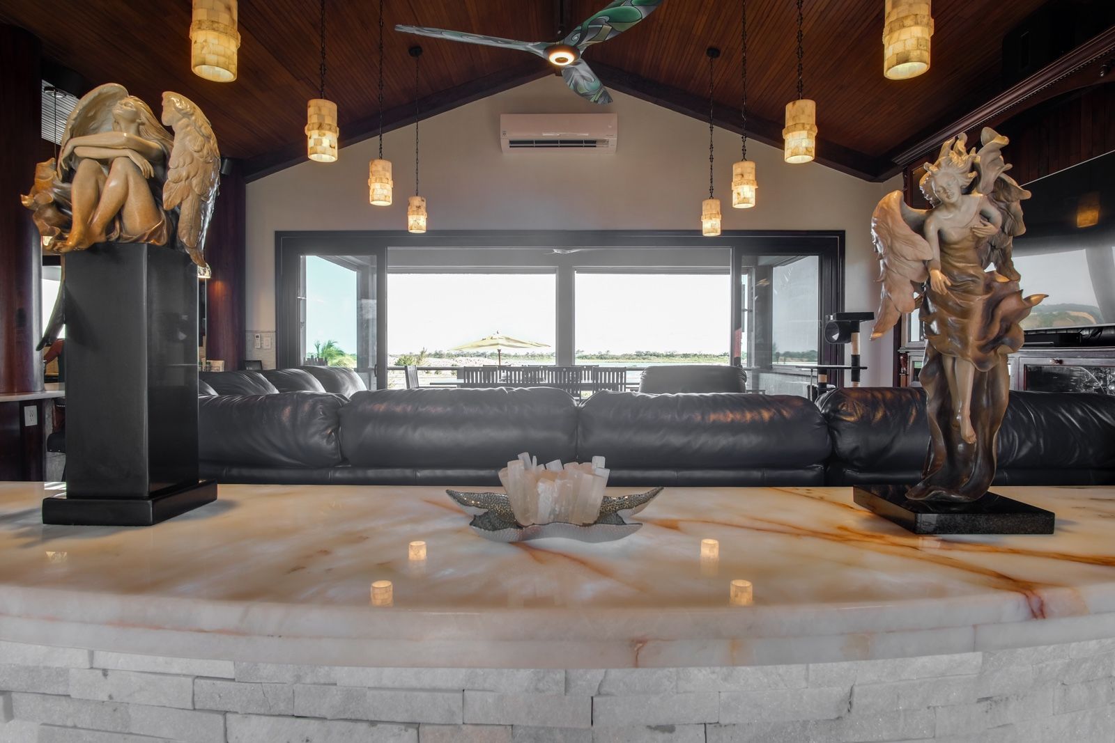 Living room with black leather sofa and large windows facing an outdoor patio