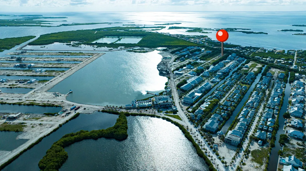 Aerial view of waterfront homes, green mangroves and calm bay water