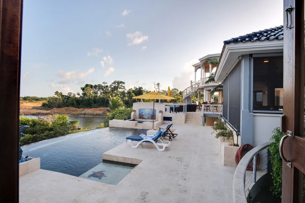 Infinity pool with turtle mosaic, loungers and yellow umbrella beside villa terrace