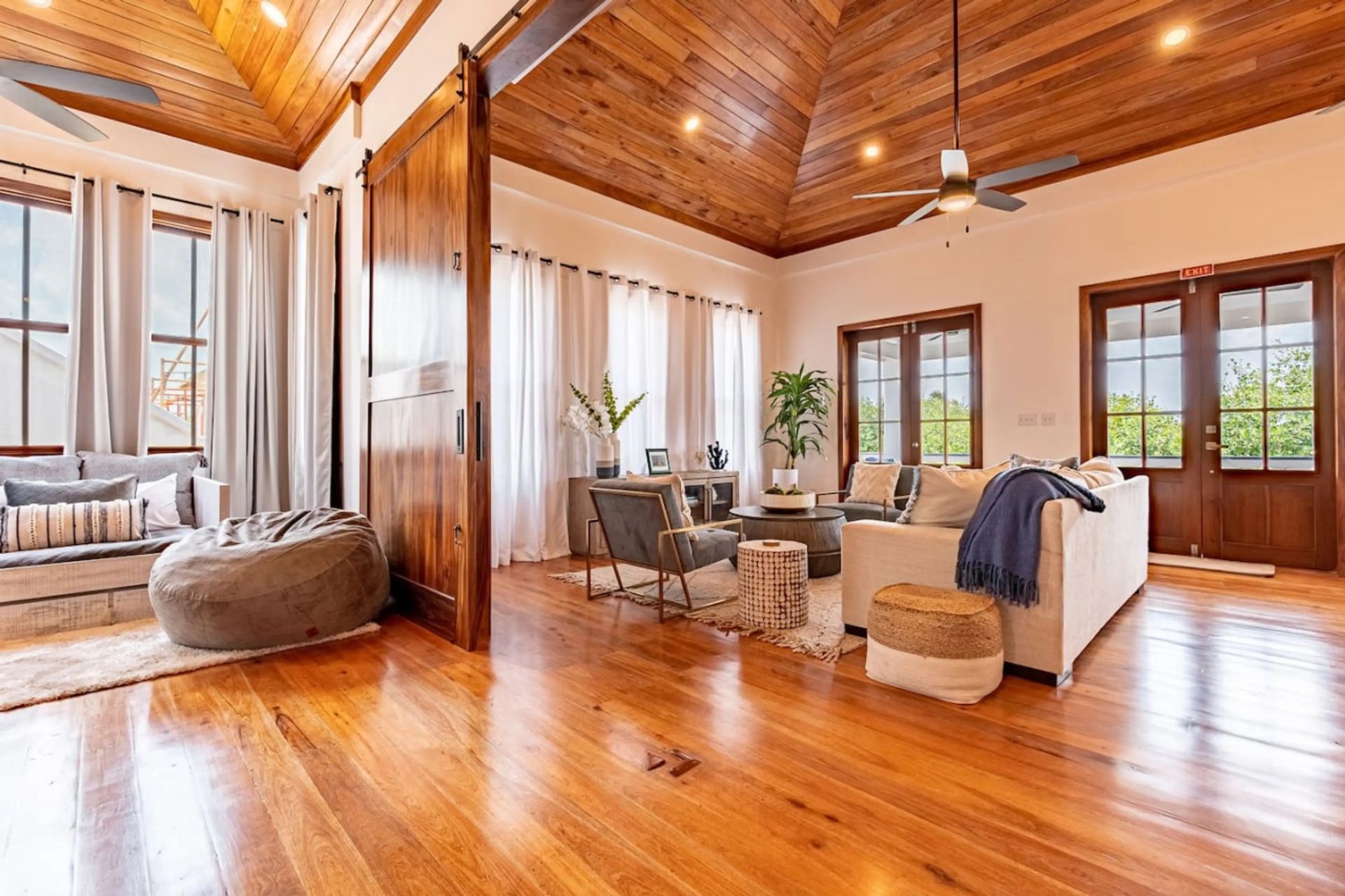 Living room with wood-paneled vaulted ceiling and sheer white curtains