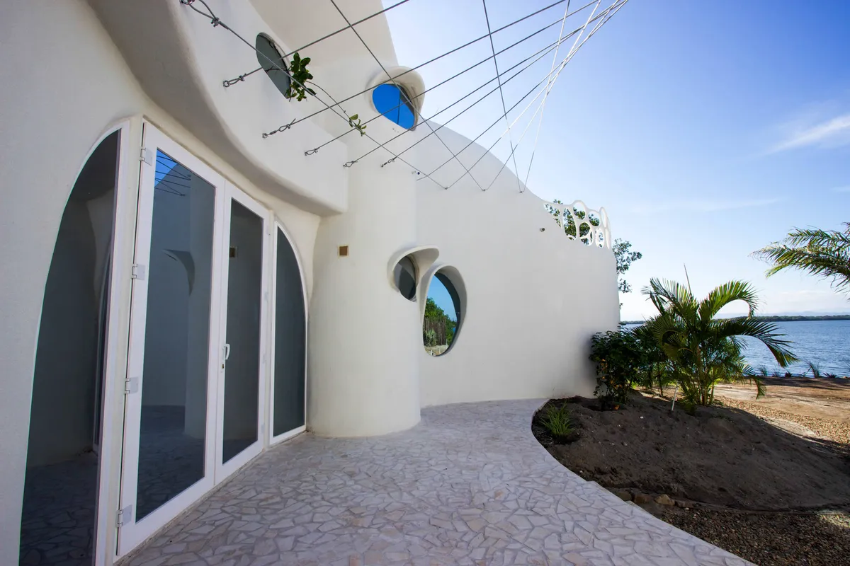 Curved white wall with oval openings and wire mesh overhead