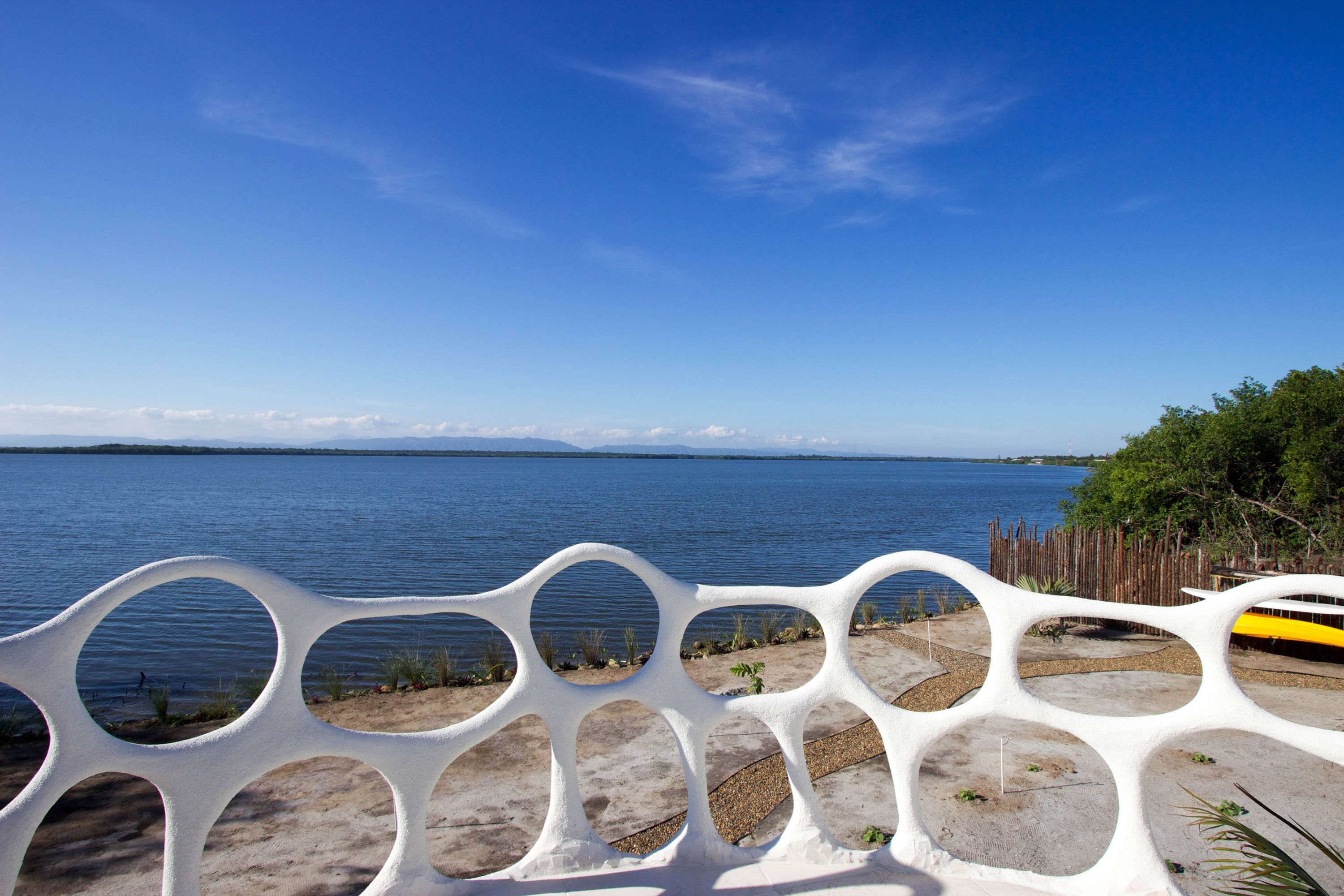 White sculpted railing with circular openings framing a calm lake view