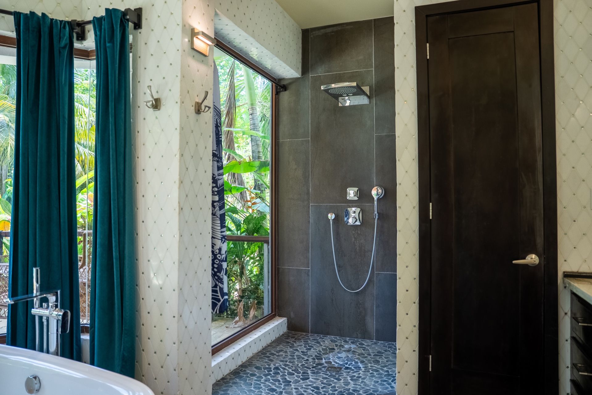 Open-air shower with dark slate tiles, rainfall head and pebble floor