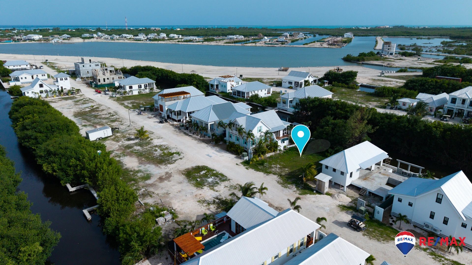 Aerial view of vacant lot beside white coastal homes with metal roofs