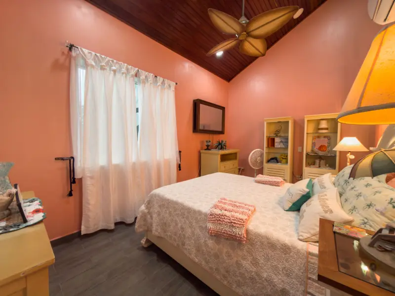 Bedroom with coral walls, wood ceiling and white sheer curtains