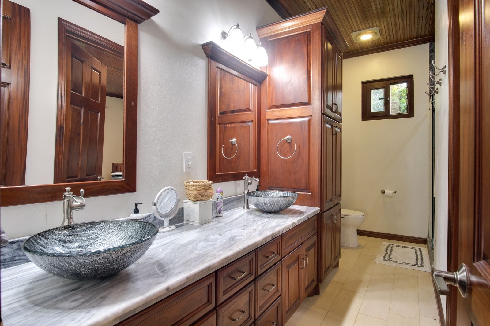 Bathroom vanity with marble counter, vessel sinks and dark wood cabinets