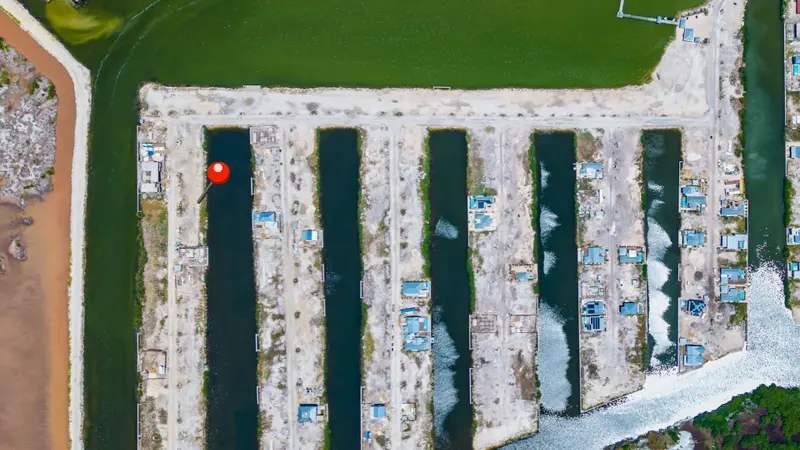 Aerial view of narrow land parcels divided by canals with a few blue-roofed buildings