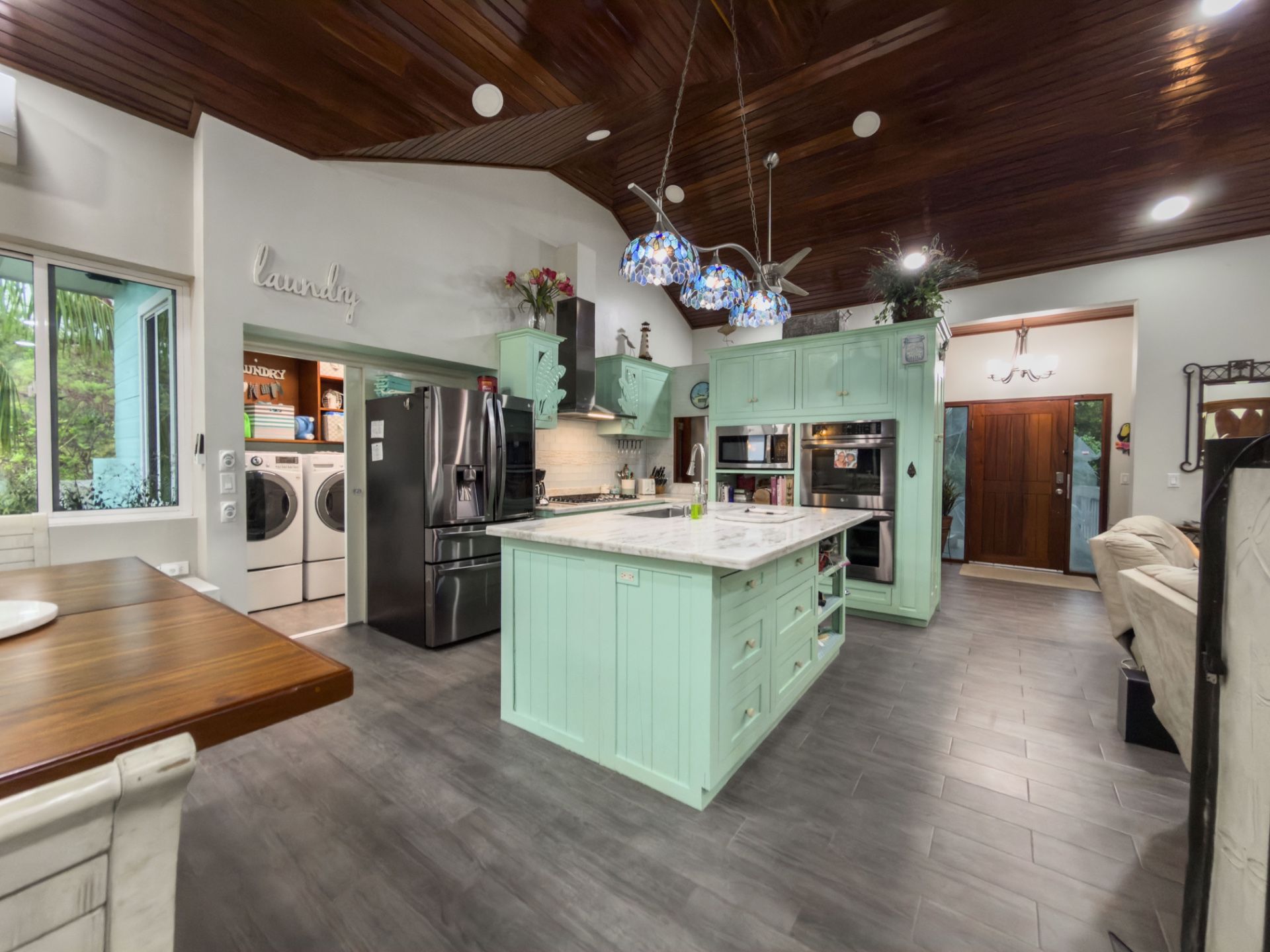 Kitchen with mint green cabinets, marble island and stained wood ceiling