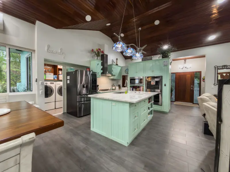 Kitchen with mint green cabinets, marble island and stained wood ceiling