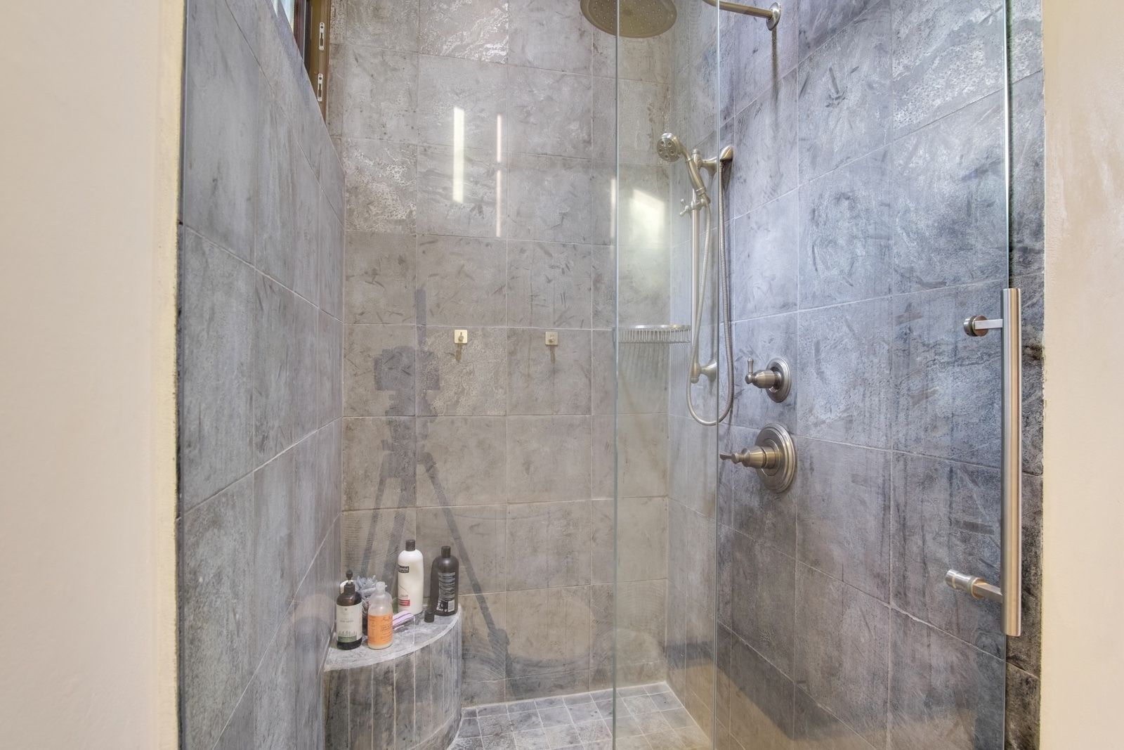 Walk-in shower with grey stone-look tiles, brushed nickel fixtures and glass enclosure