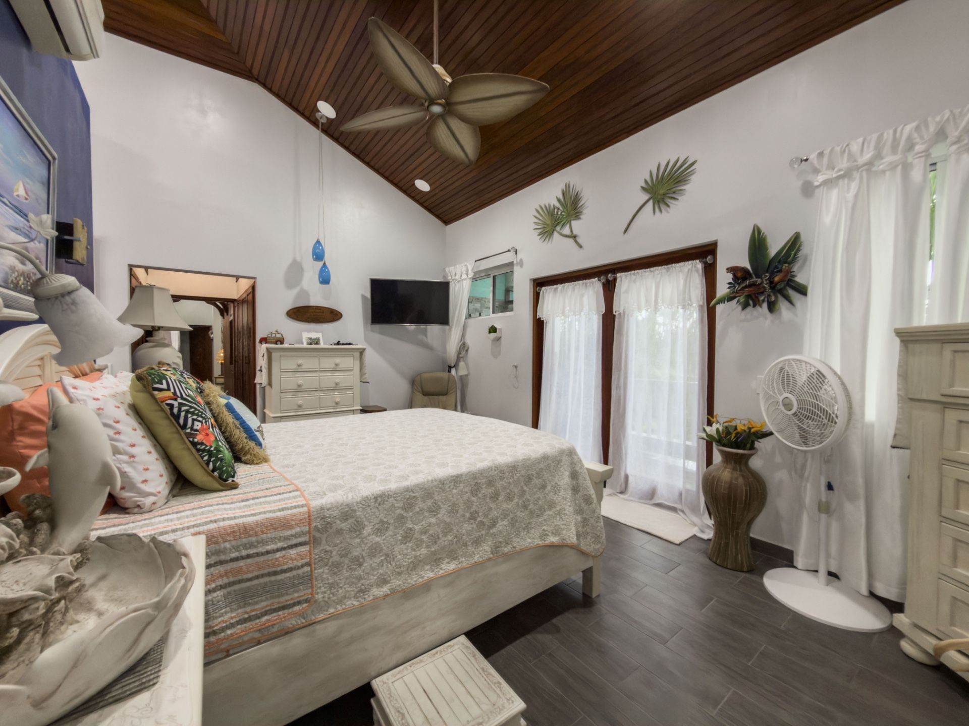 Bedroom with wood plank ceiling, ceiling fan and white curtained glass doors