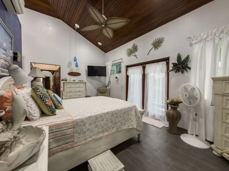 Bedroom with wood plank ceiling, ceiling fan and white curtained glass doors
