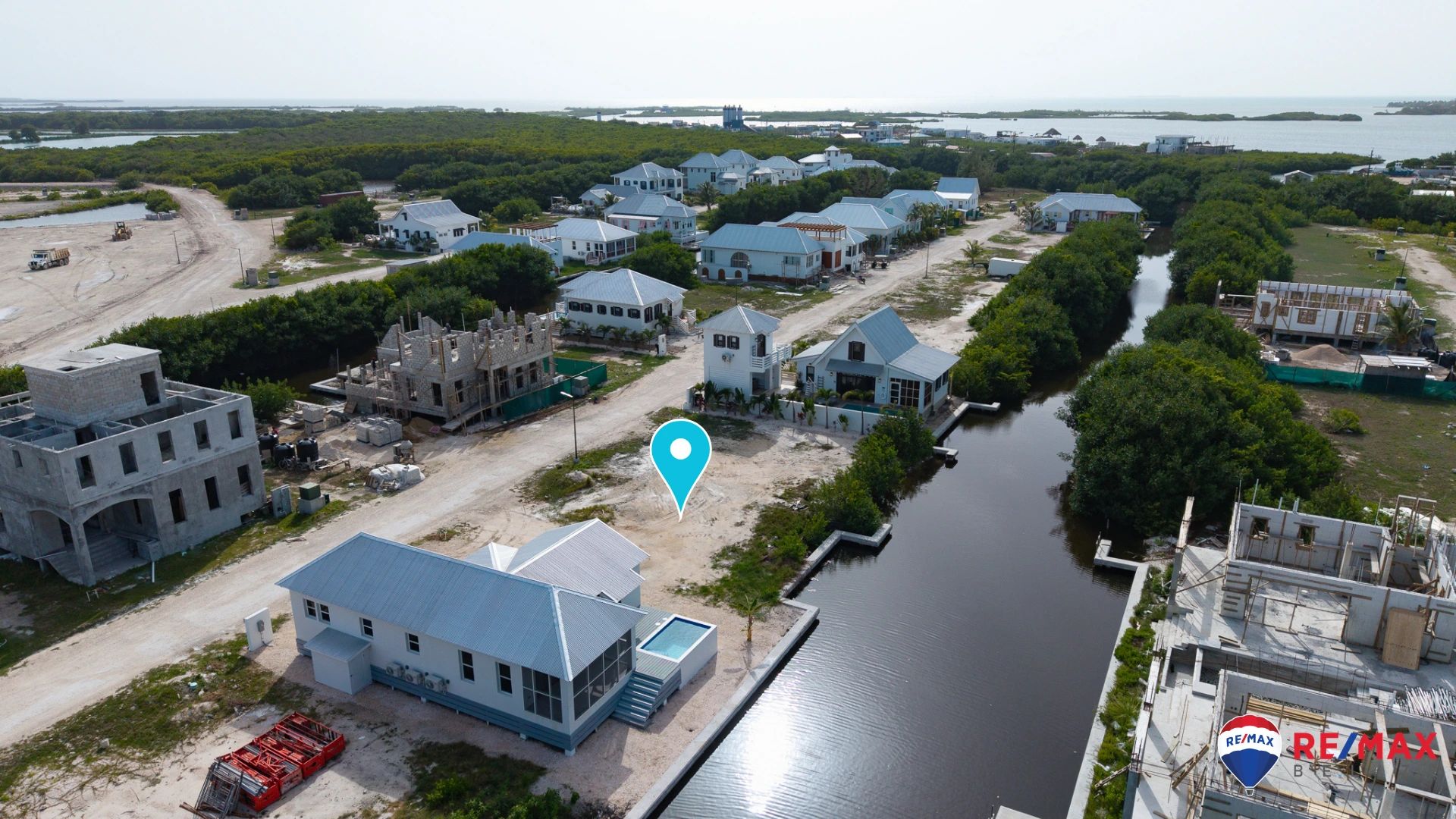 Aerial view of a cleared sandy lot beside a canal with a marker pin