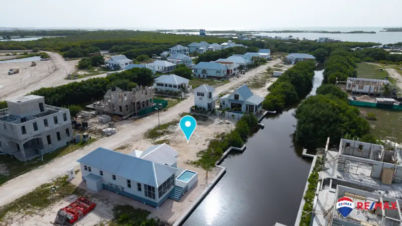 Aerial view of a cleared sandy lot beside a canal with a marker pin