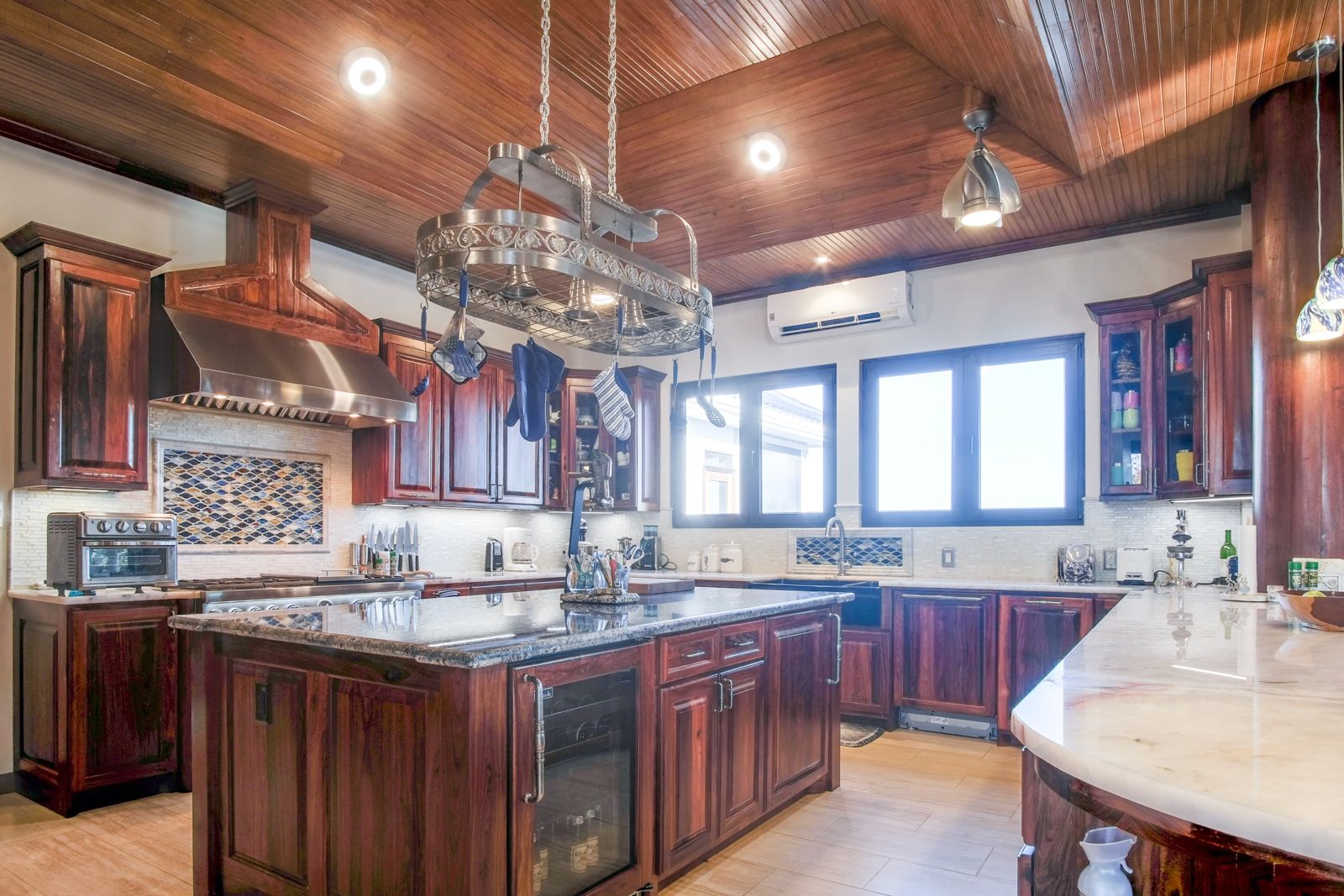 Kitchen with dark wood cabinets, granite island and hanging pot rack