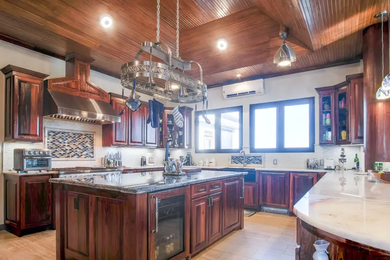 Kitchen with dark wood cabinets, granite island and hanging pot rack