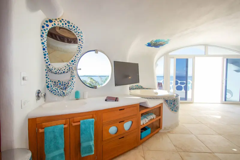 Room with round window, wall-mounted TV and wooden drawers with blue pebble handles