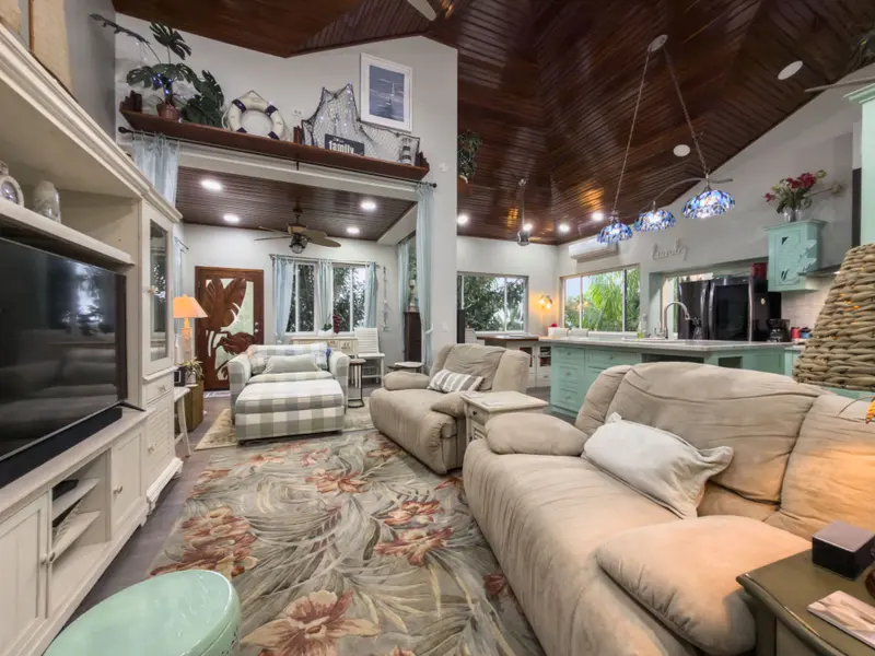 Living room with beige recliner sofas and floral area rug under wood-paneled ceiling