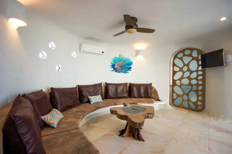 Lounge with curved brown sofa, live-edge wood table and lionfish mural