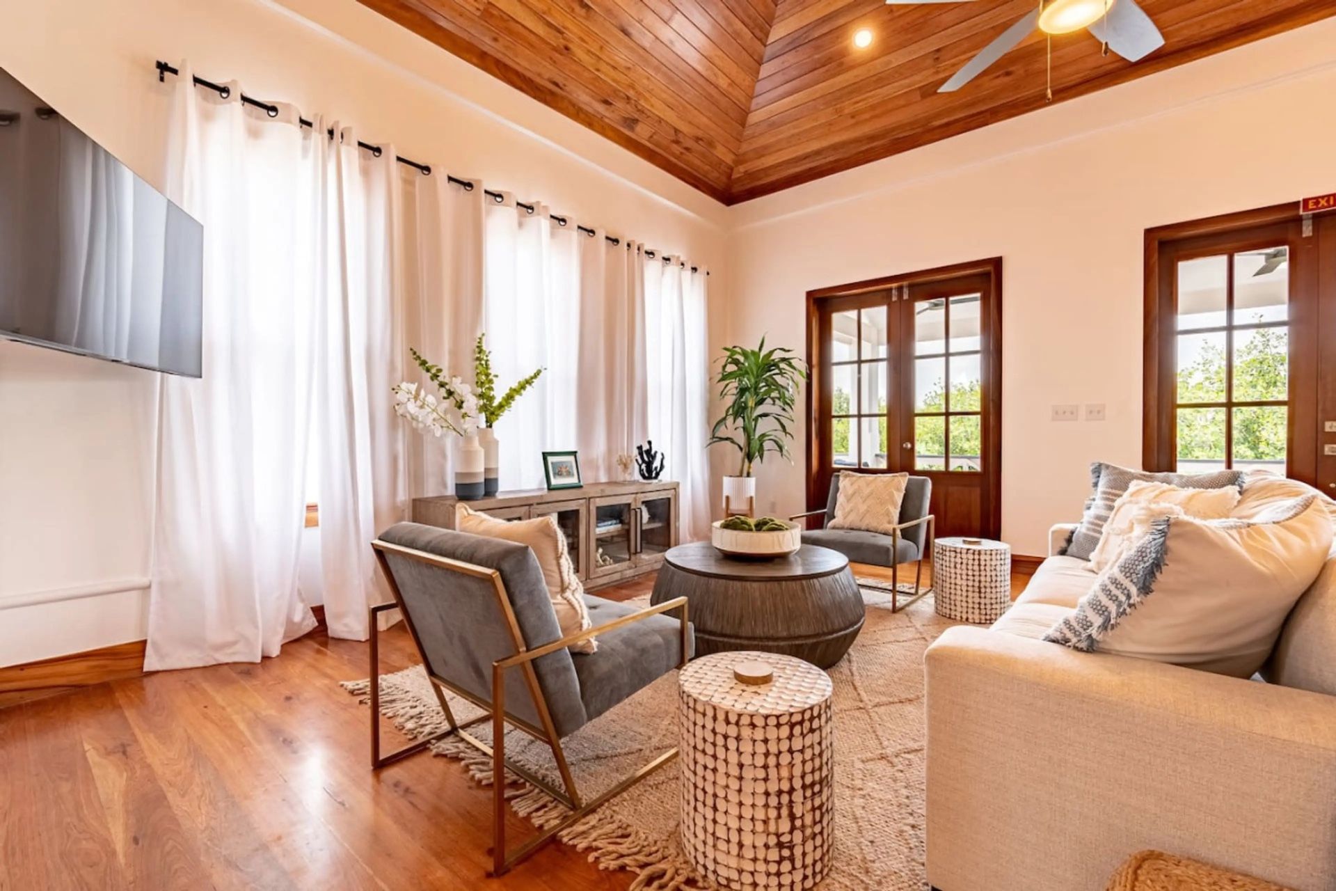 Living room with wood-paneled vaulted ceiling and grey armchairs on a woven rug