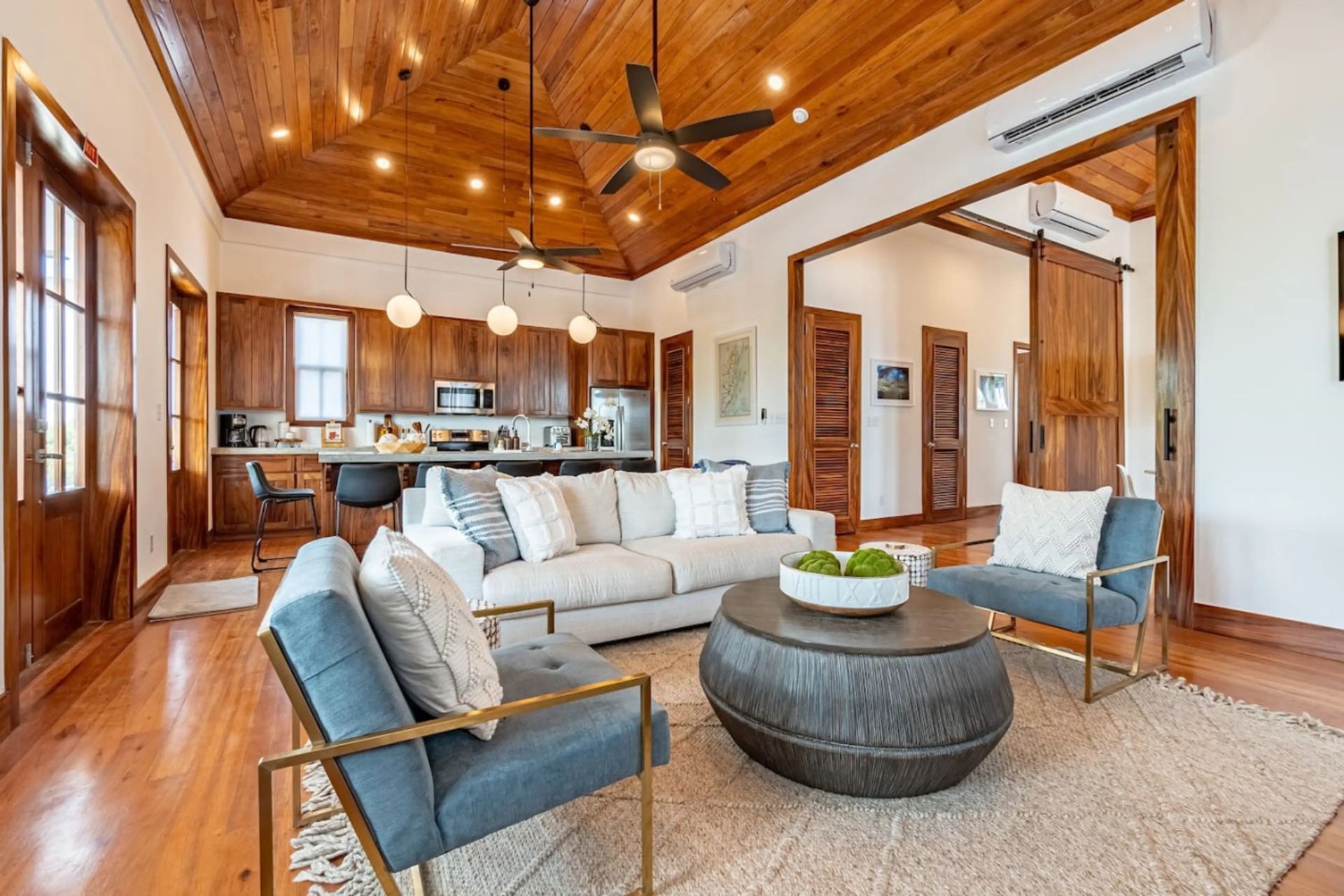 Open living room with cream sofa, wood vaulted ceiling and round coffee table