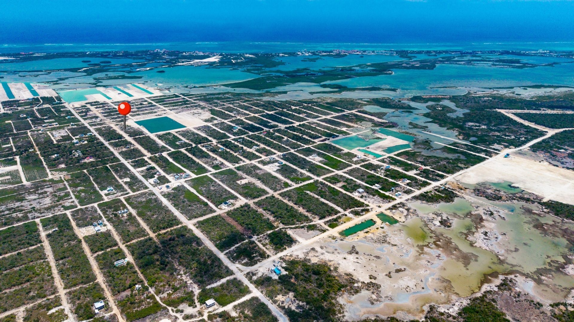 Aerial view of a gridded lot subdivision beside turquoise coastal water