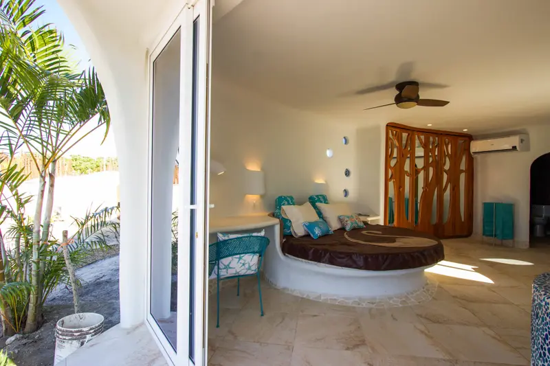 Built-in curved bed alcove with teal sea-themed cushions and a teal metal chair