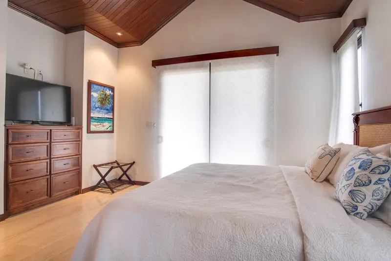 Bedroom with white quilted bedspread, wood-paneled vaulted ceiling and damask sheer panels