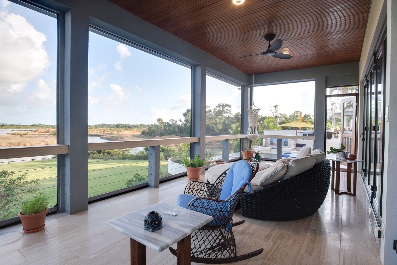 Covered veranda with wood ceiling, rattan rocking chair and marble side table