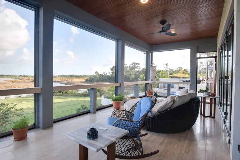 Covered veranda with wood ceiling, rattan rocking chair and marble side table