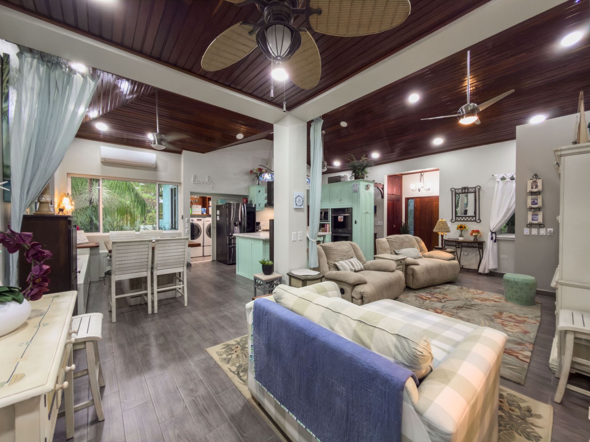 Open living room with mint cabinets, beige recliners and wood-paneled ceiling