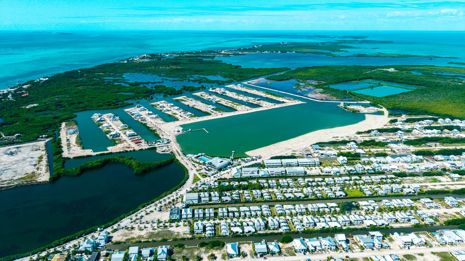 Aerial view of canal-side homes, marina basins and turquoise sea beyond