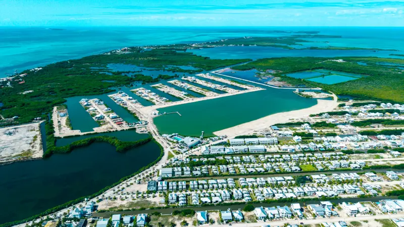 Aerial view of canal-side homes, marina basins and turquoise sea beyond