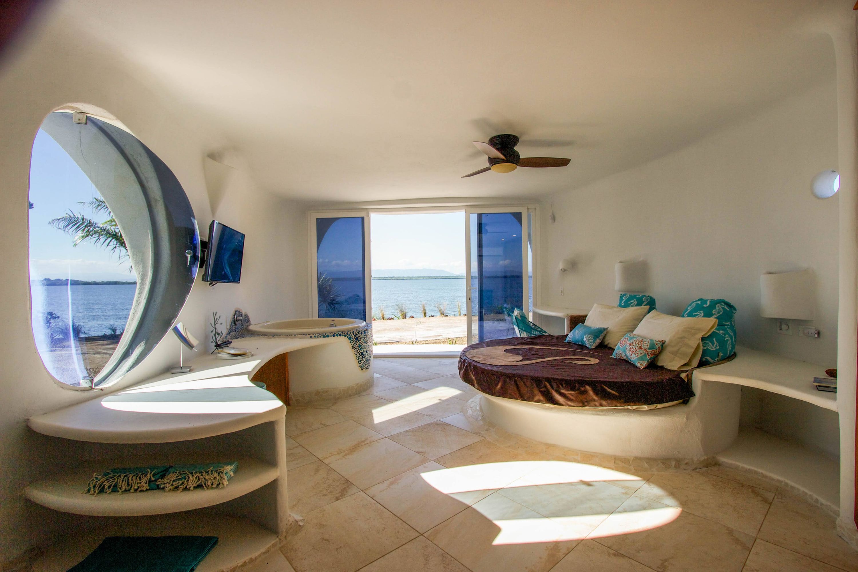 Bright room with tiled floor, ceiling fan and open glass doors to water