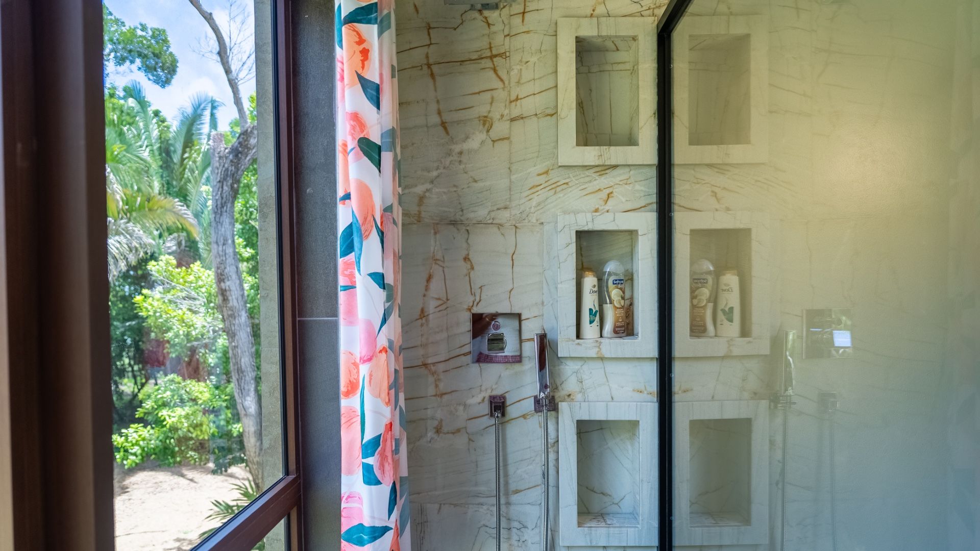 Shower with veined marble-look tile, recessed niches and a handheld showerhead