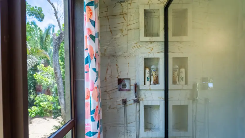 Shower with veined marble-look tile, recessed niches and a handheld showerhead