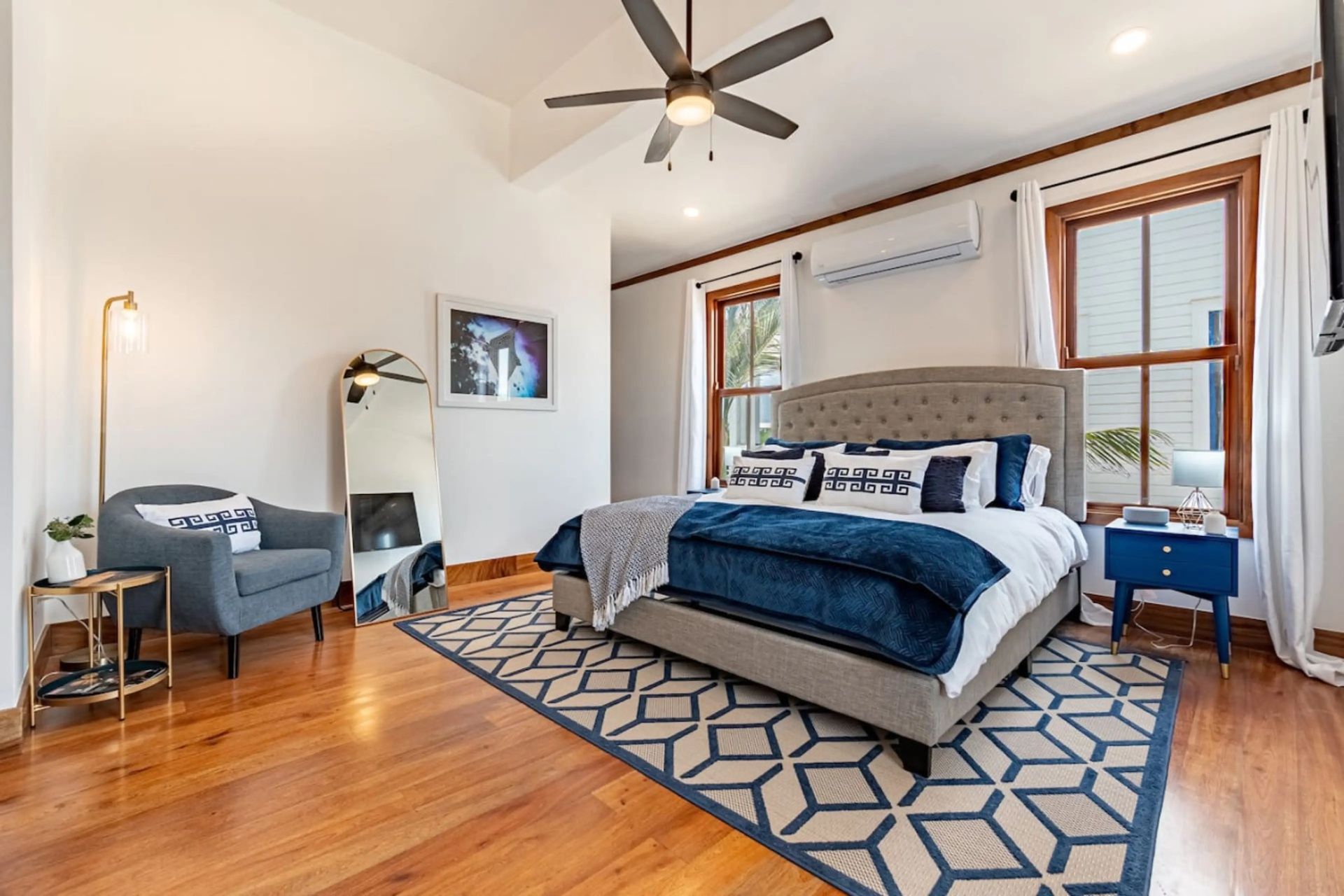 Bedroom with navy bedding, tufted grey headboard and patterned rug