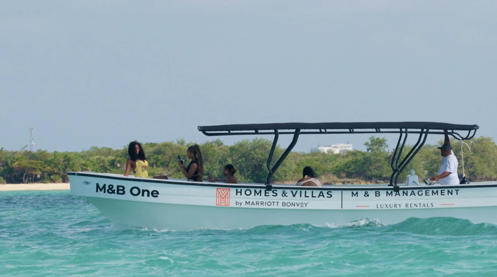 White boat with black canopy and three people on turquoise water
