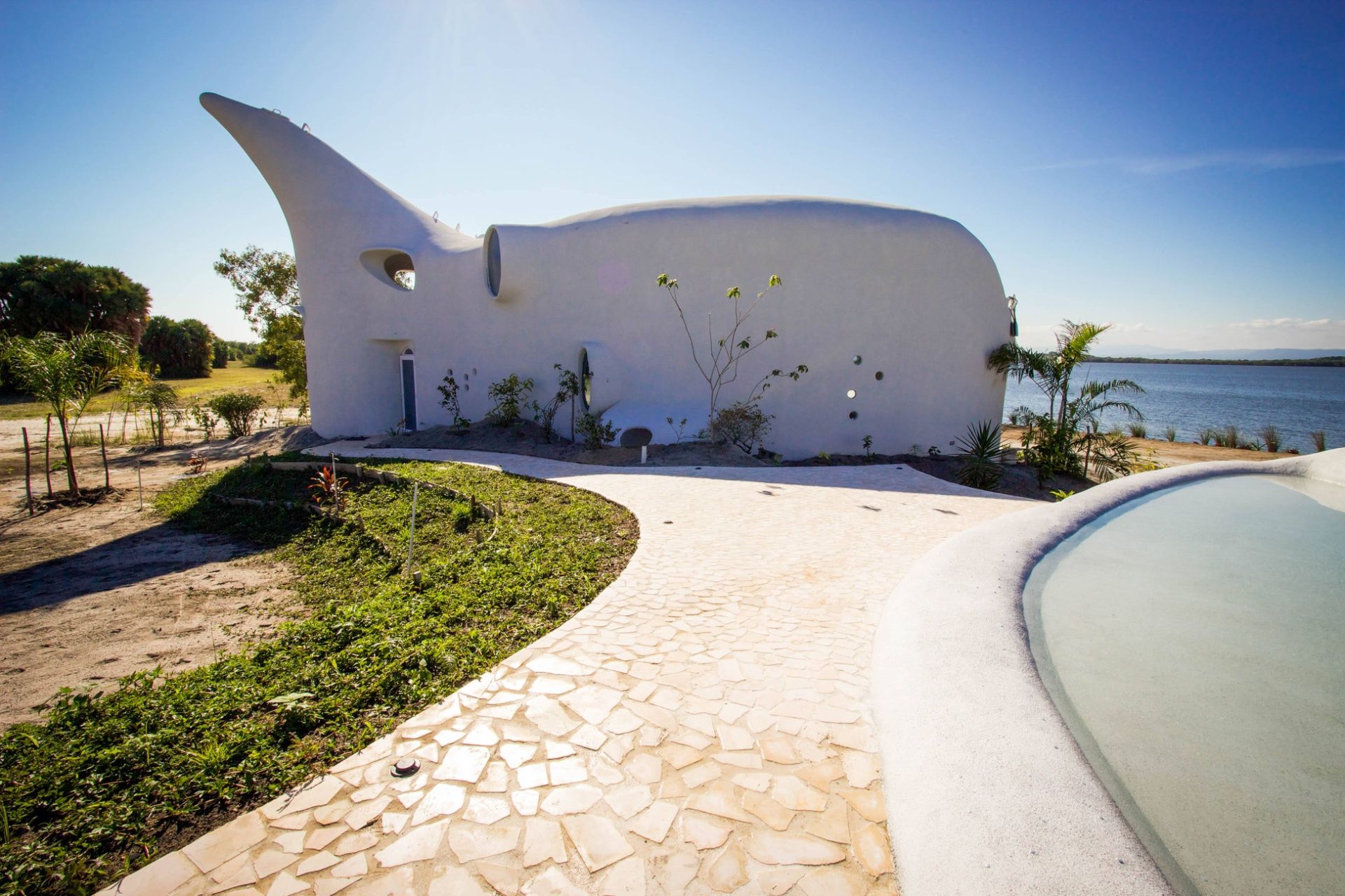 Curved white rendered building with round windows beside a flagstone path