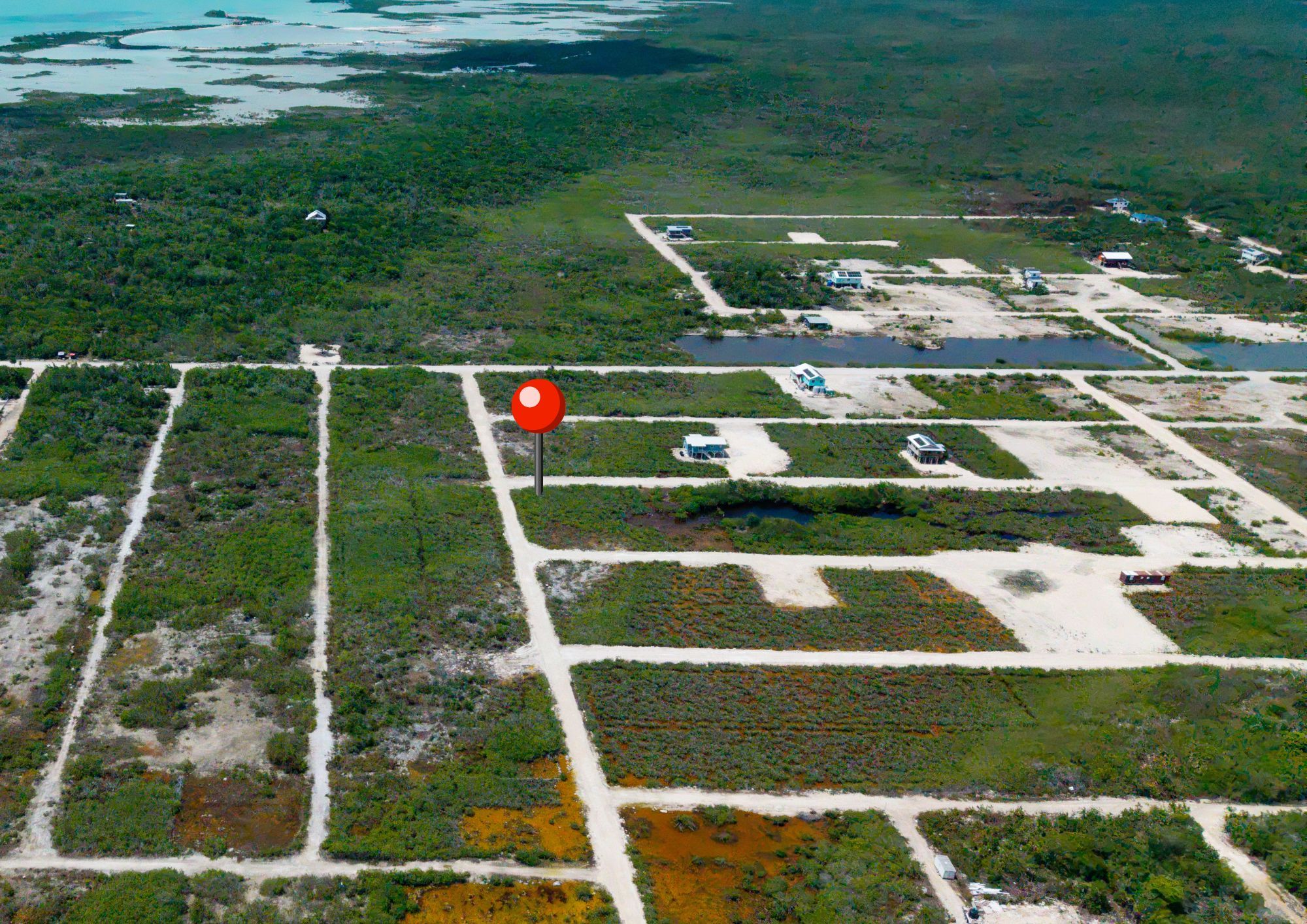 Aerial view of gridded land lots with dirt roads and scattered small buildings