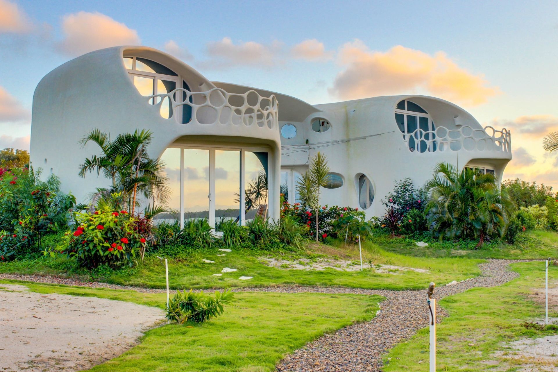 Exterior of a white curved building with circular windows and a perforated balcony railing