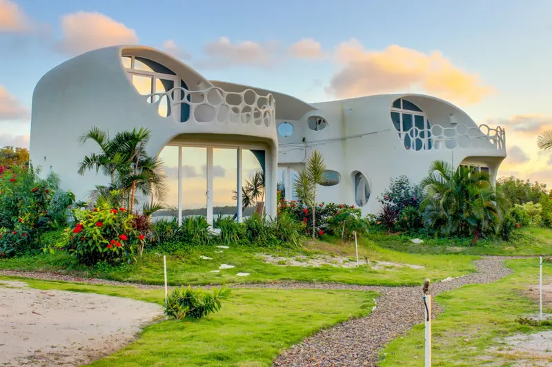 Exterior of a white curved building with circular windows and a perforated balcony railing