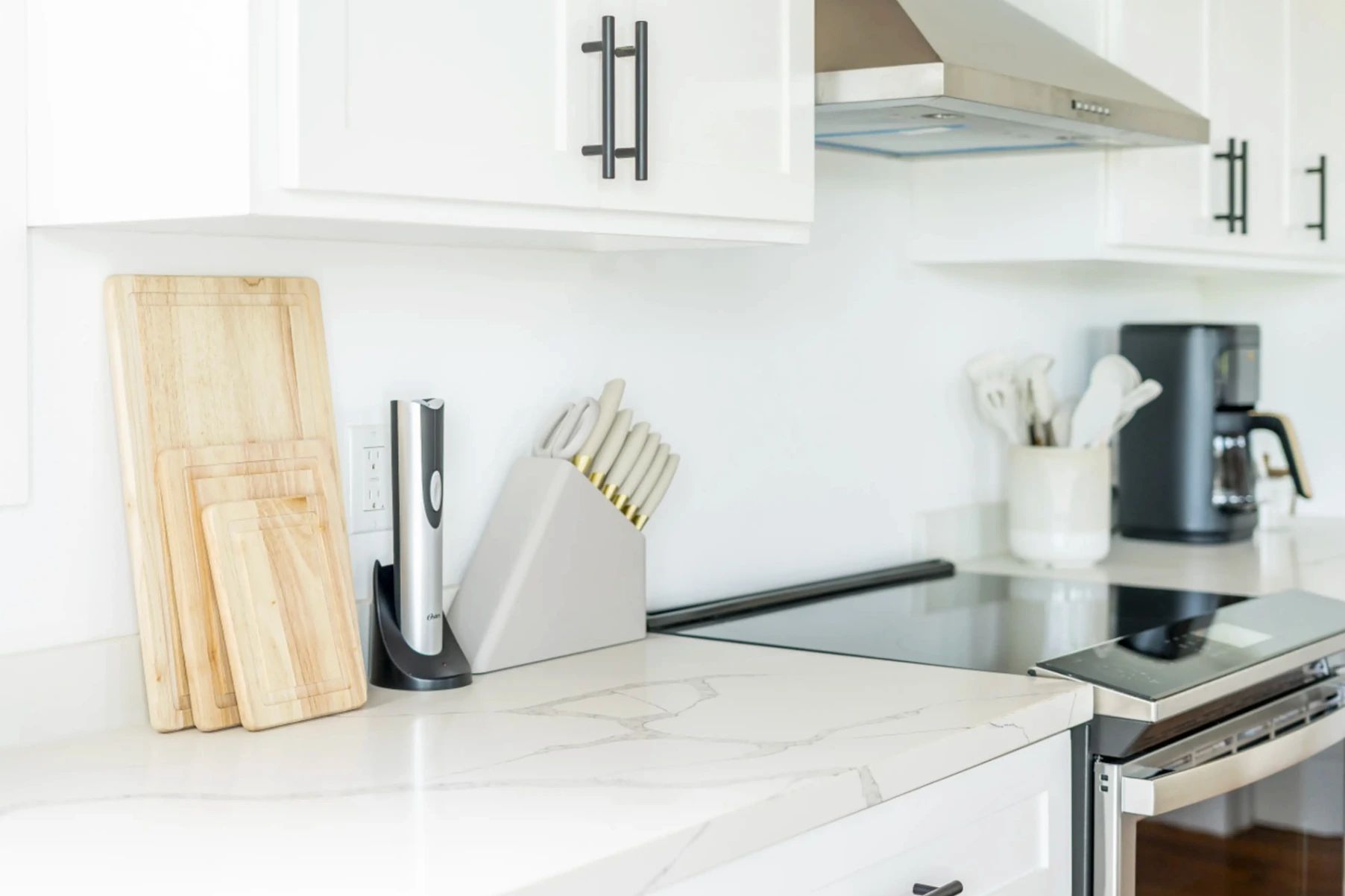 Kitchen counter with knife block, scissors and electric sharpener beside white cabinets